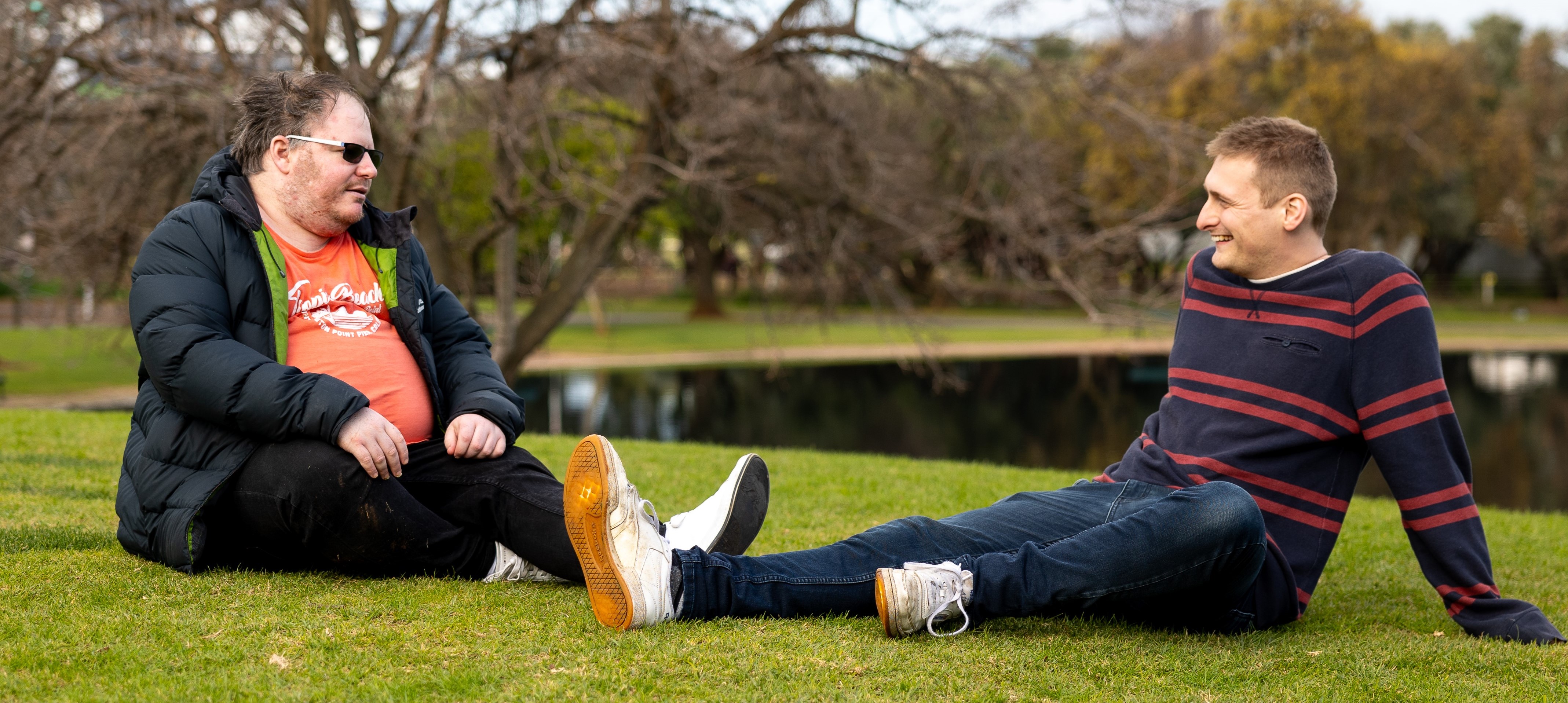 A support worker and participant sitting in a park